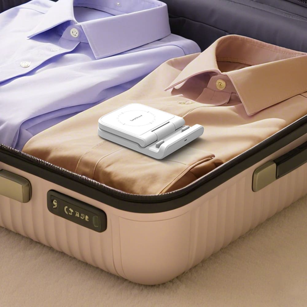 White compact SwanScout 501S foldable charger packed flat inside an open suitcase with shirts for travel
